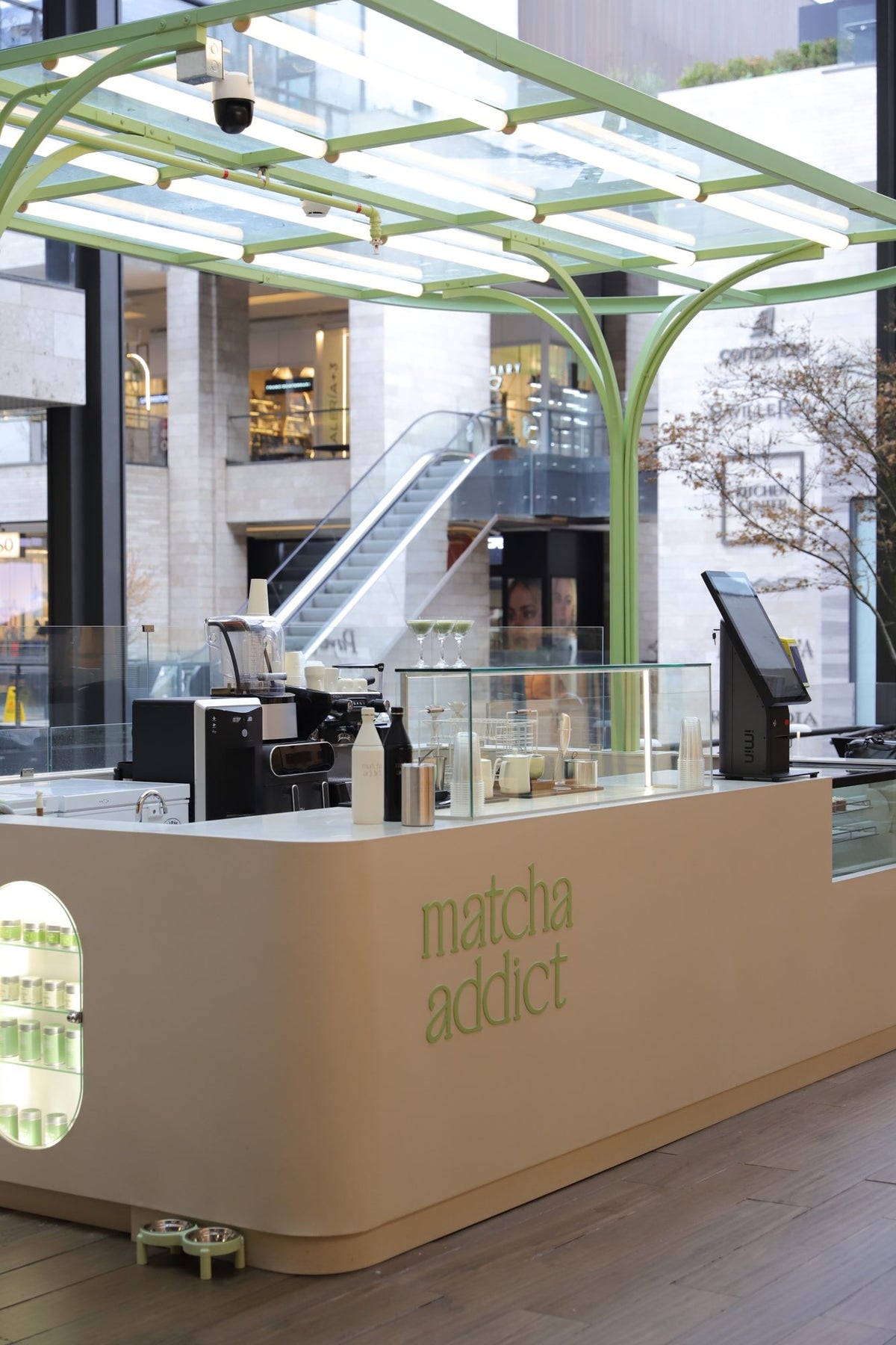 Barra de Matcha Addict Casacostanera con la vitrina de latas de matcha y la máquina de café